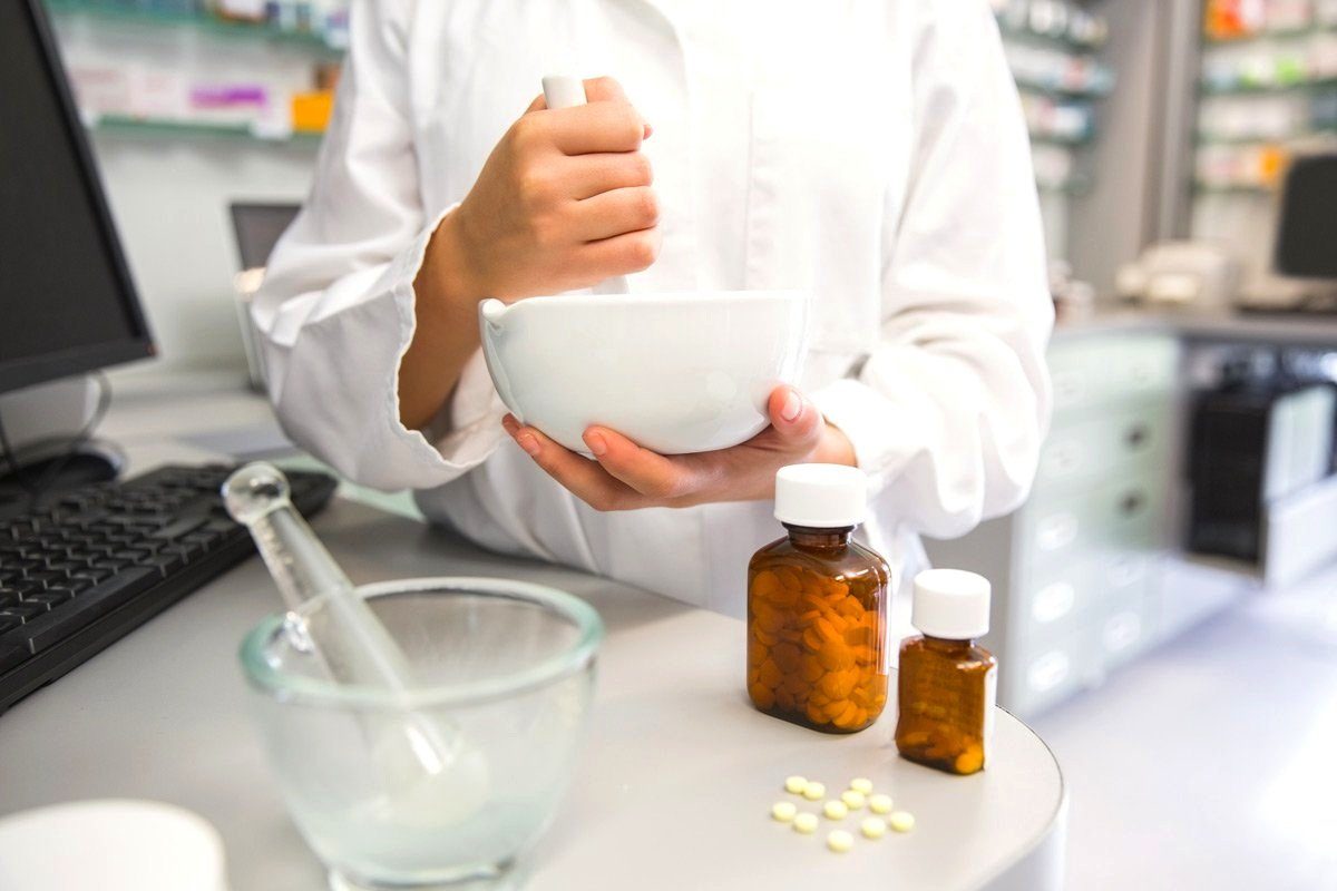 Pharmacist compounding medication with a mortar and pestle
