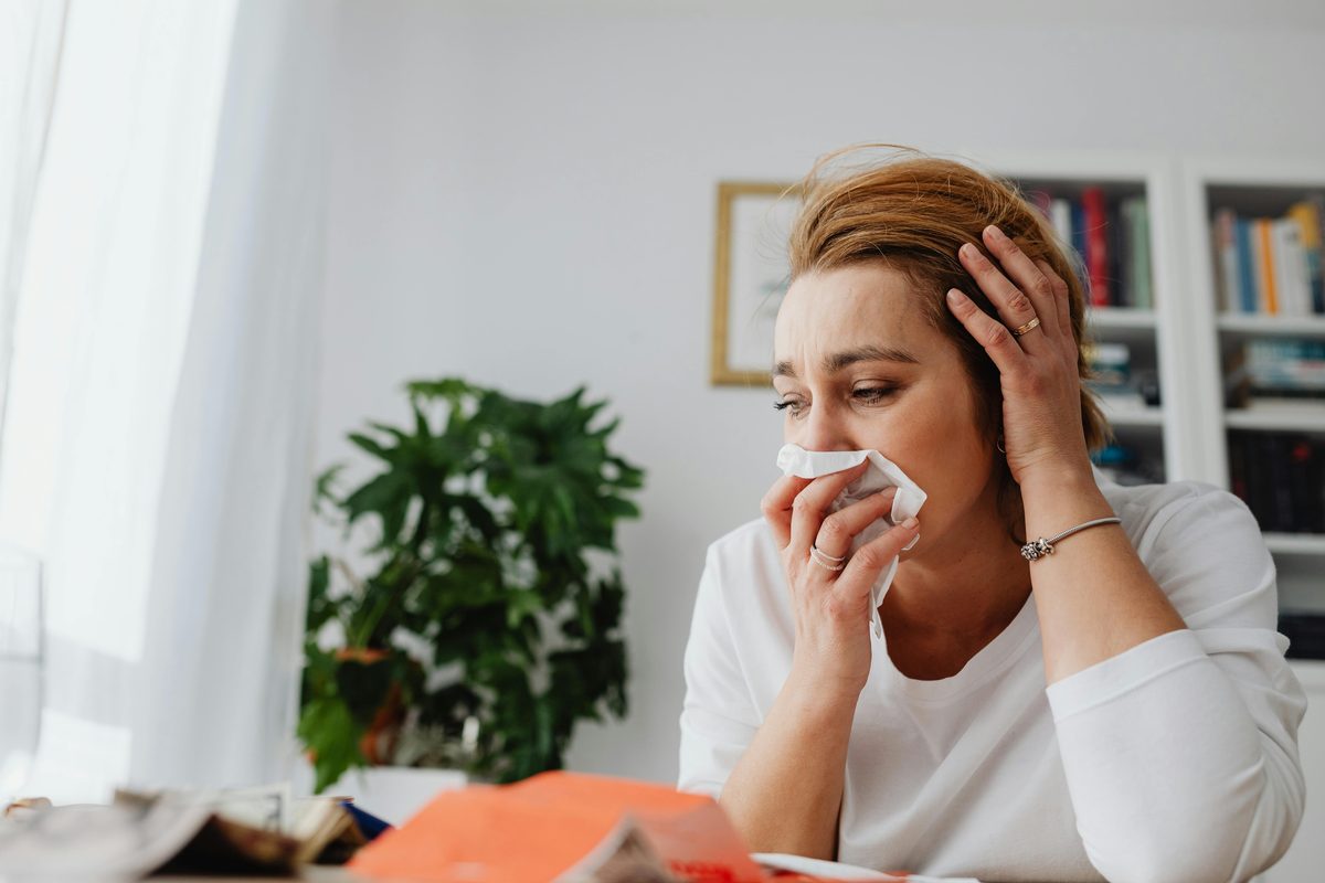 A woman feeling unwell at home with a tissue